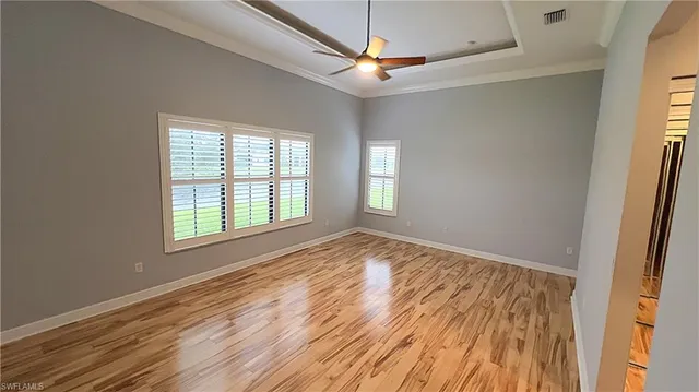 a view of empty room with wooden floor and fan