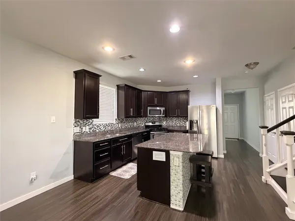 a kitchen with stainless steel appliances kitchen island granite countertop a stove refrigerator and cabinets