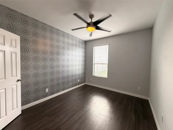 an empty room with wooden floor fan and windows