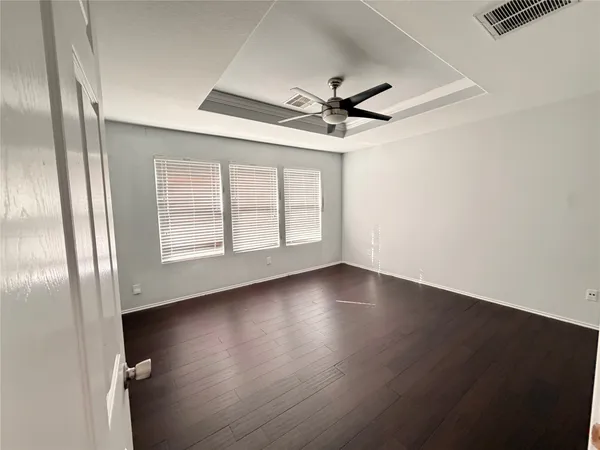 an empty room with wooden floor fan and windows
