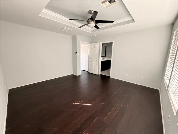 an empty room with wooden floor and ceiling fan