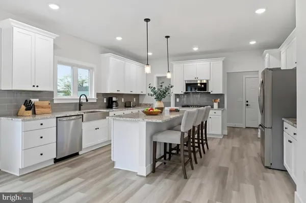 a kitchen with stainless steel appliances kitchen island granite countertop a refrigerator a stove a sink a dining table and chairs with wooden floor