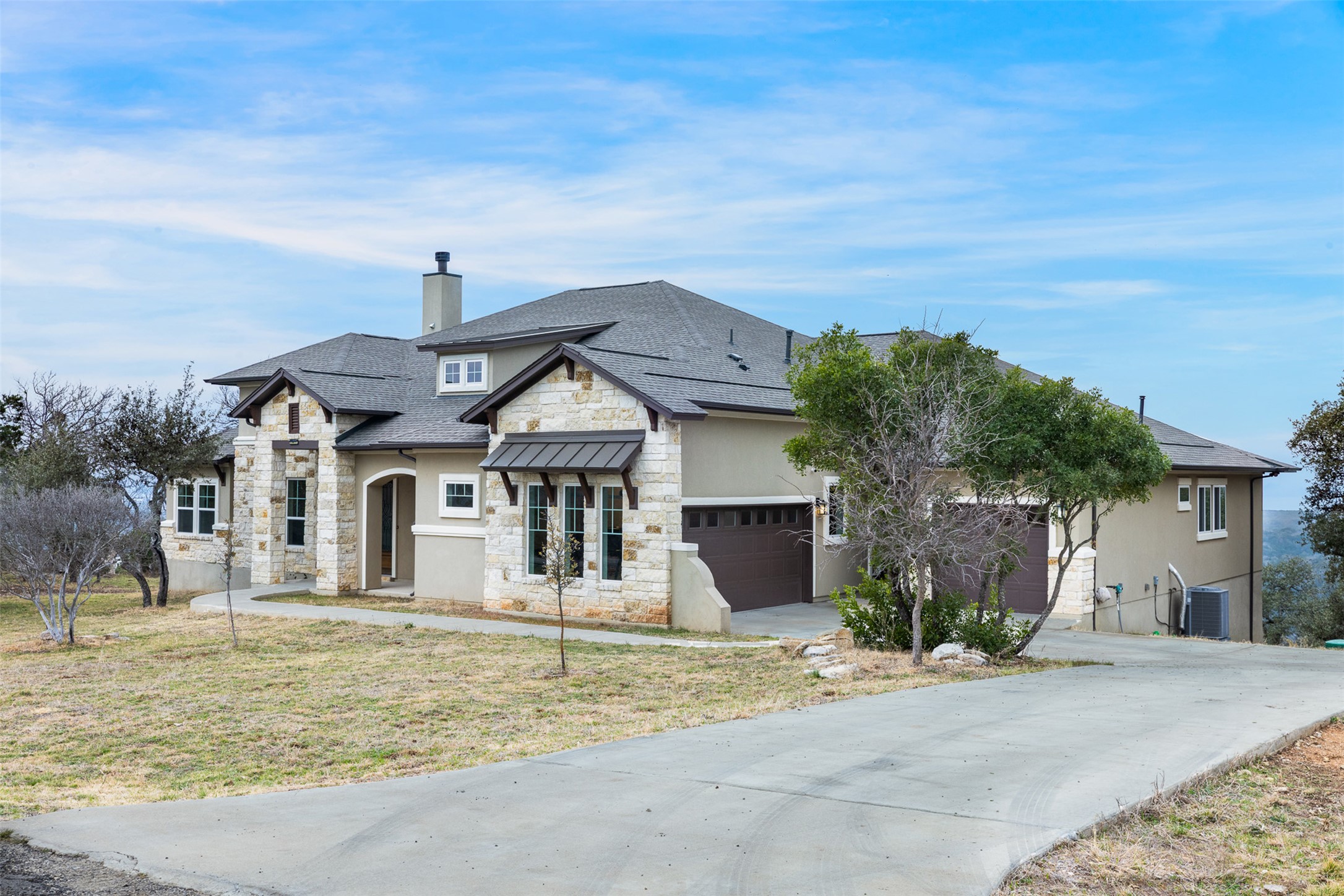 235 Chestnut Crossing Burnet, TX 78611 - Photo 33 of 39 View of front of property featuring stone siding, concrete driveway, stucco siding, and a chimney