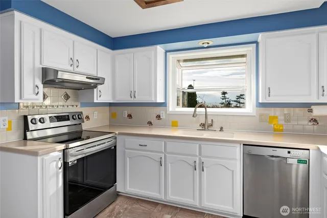 a kitchen with cabinets appliances a sink and a window