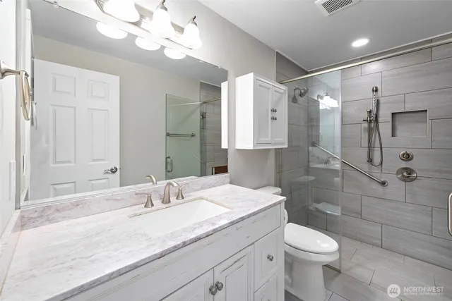 a bathroom with a granite countertop sink a toilet and shower