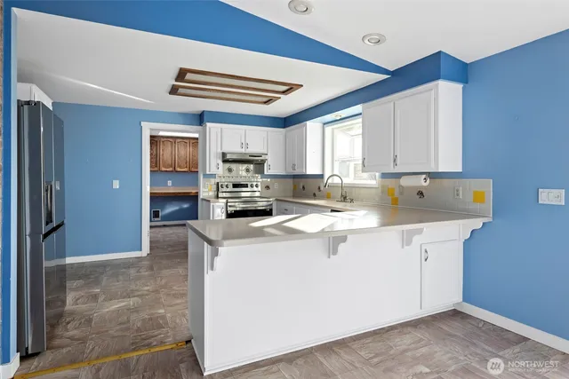 a kitchen with stainless steel appliances granite countertop a sink a stove and a refrigerator