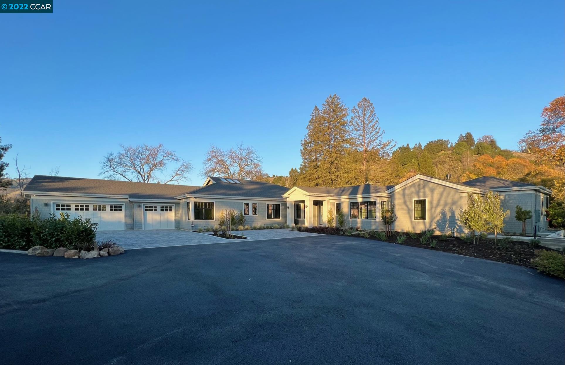 a view of a white house with a big yard and potted plants