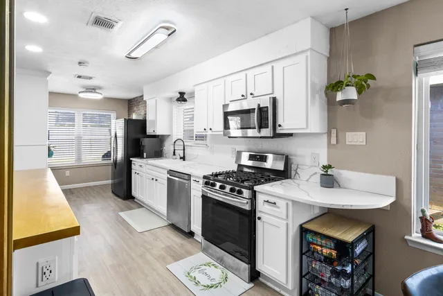 a kitchen with stainless steel appliances a stove a sink cabinets and a wooden floor