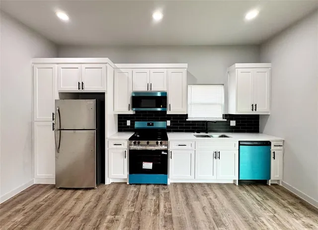a kitchen with a refrigerator a stove top oven and a hard wood floor