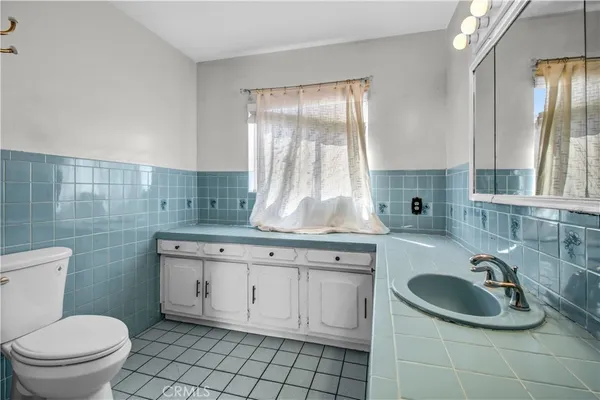 a bathroom with a sink toilet a mirror and window