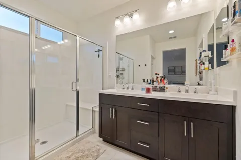 a bathroom with a double vanity sink mirror and shower