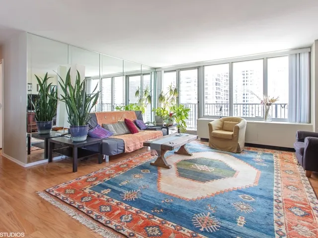 a living room with furniture large windows and wooden floor