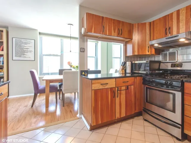 a kitchen with stainless steel appliances granite countertop a stove a refrigerator a kitchen island a table and chairs