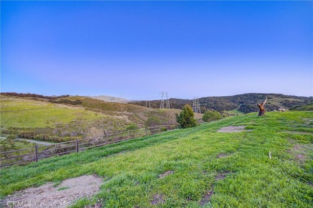 a view of a lush green field with mountains in the background
