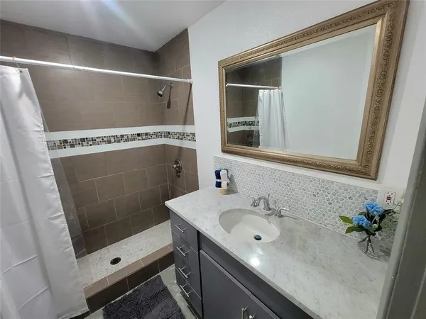 a bathroom with a shower sink and mirror