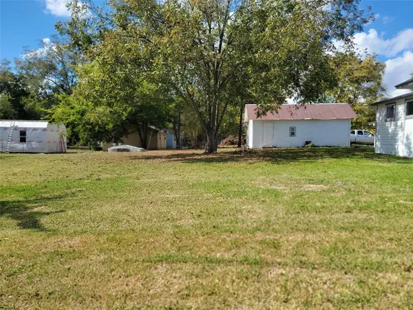 a view of a house with a yard and a large tree