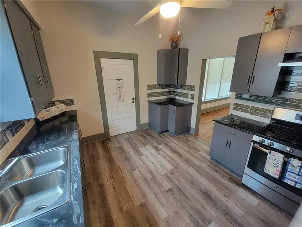 a kitchen with stainless steel appliances a stove refrigerator and wooden floor