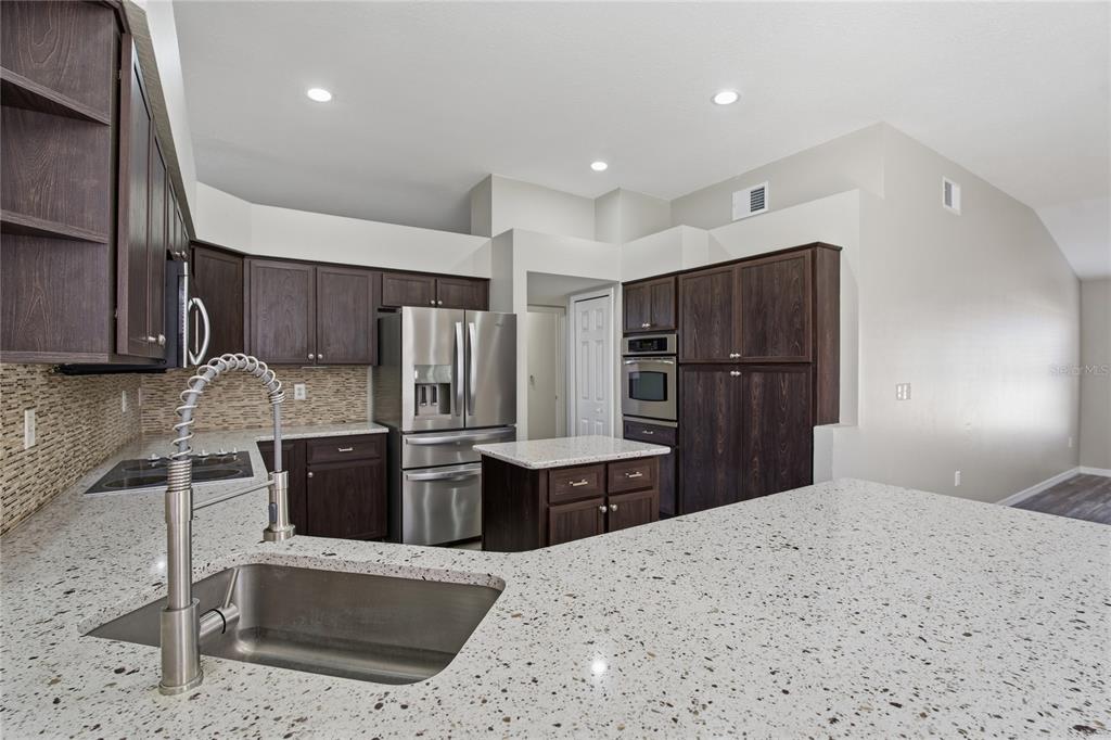 17431 Isbell Lane Odessa, FL 33556 - Photo 11 of 47 a kitchen with stainless steel appliances kitchen island granite countertop a refrigerator and a sink