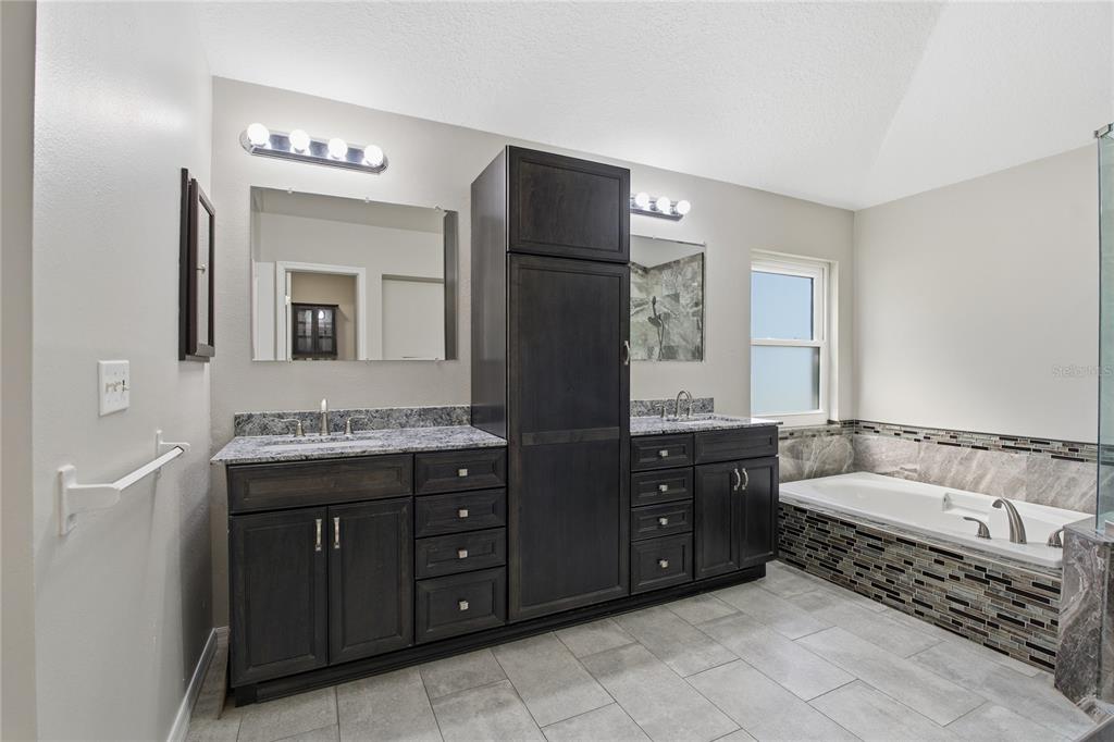 17431 Isbell Lane Odessa, FL 33556 - Photo 22 of 47 a spacious bathroom with a double vanity sink a large mirror and a bathtub