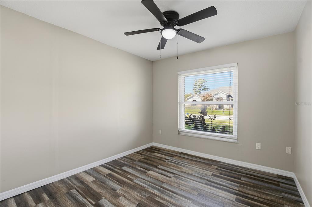 17431 Isbell Lane Odessa, FL 33556 - Photo 27 of 47 an empty room with wooden floor ceiling fan and windows