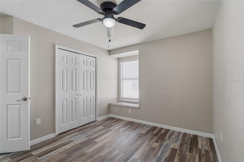 17431 Isbell Lane Odessa, FL 33556 - Photo 28 of 47 an empty room with wooden floor ceiling fan and windows