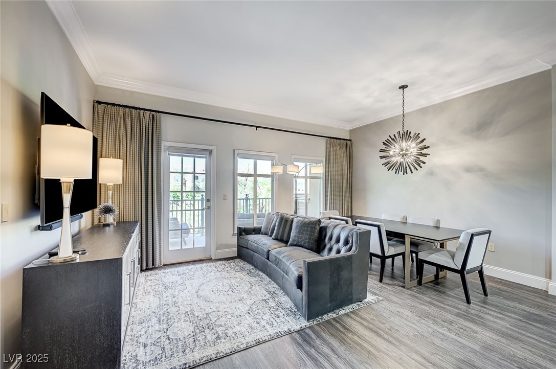 Living area with ornamental molding, light wood-style flooring, and a chandelier