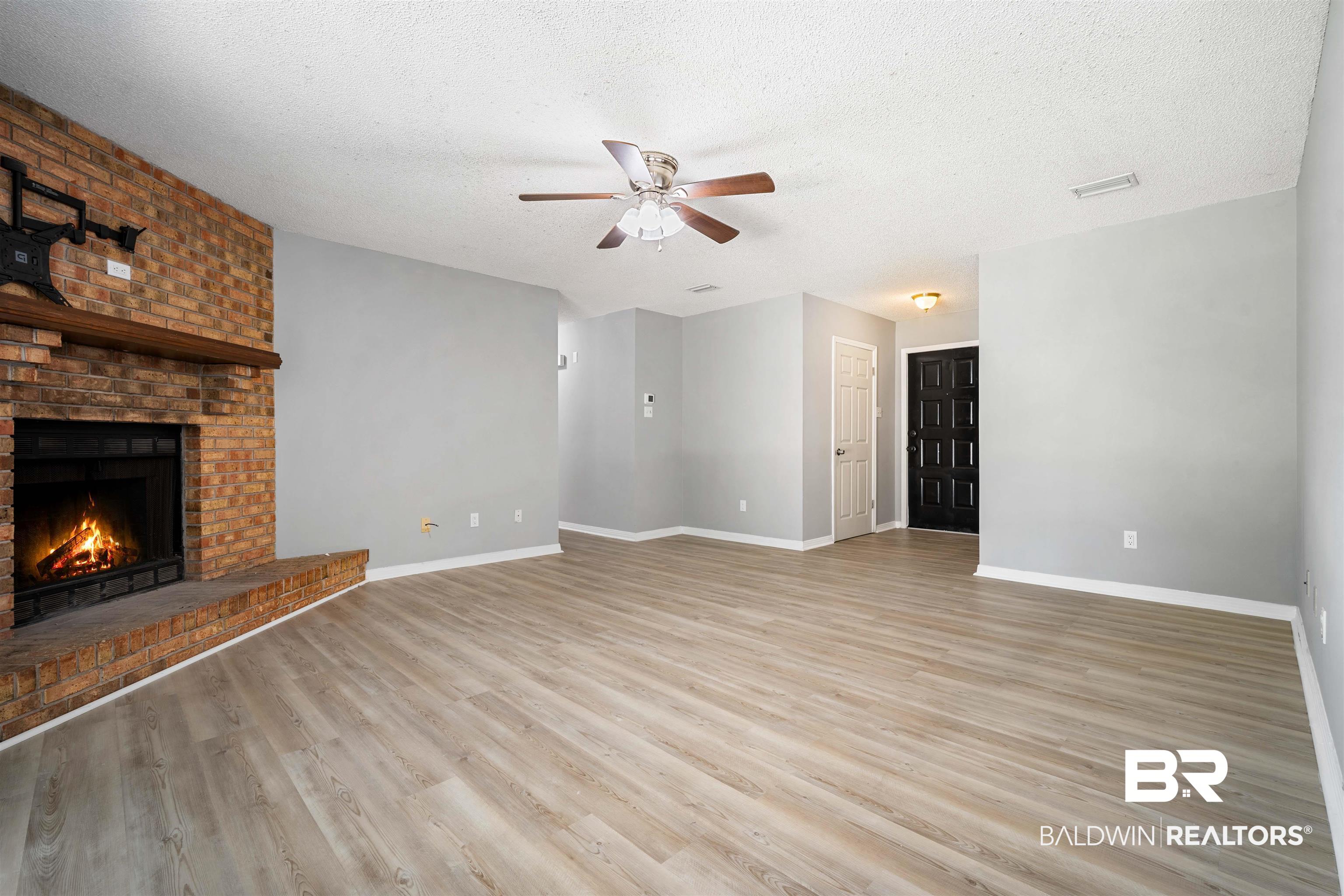 12910 Del Rio Street Grand Bay, AL 36541 - Photo 7 of 26 Unfurnished living room with a textured ceiling, light wood-style flooring, a ceiling fan, and a fireplace