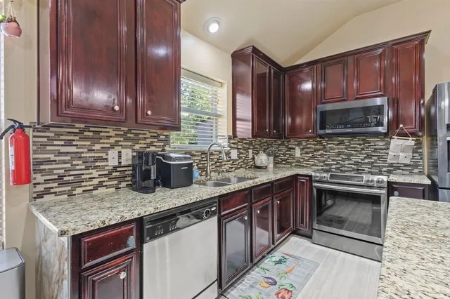 a kitchen with stainless steel appliances granite countertop a sink stove and cabinets