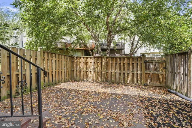 a view of backyard with wooden fence and large trees