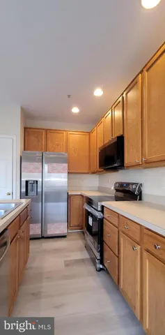 a kitchen with stainless steel appliances granite countertop a stove top oven a sink a refrigerator white cabinets and couches with wooden floor