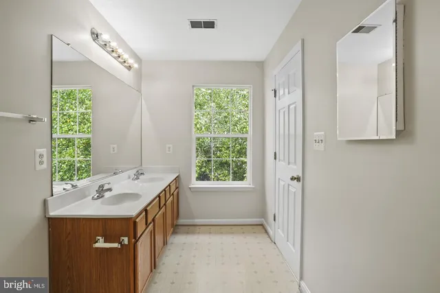 a spacious bathroom with a double vanity sink a mirror and a bathtub