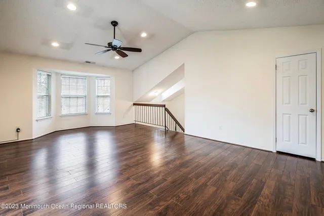 a view of empty room with wooden floor and fan