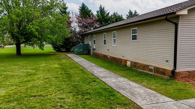 a view of a house with a yard and a large tree