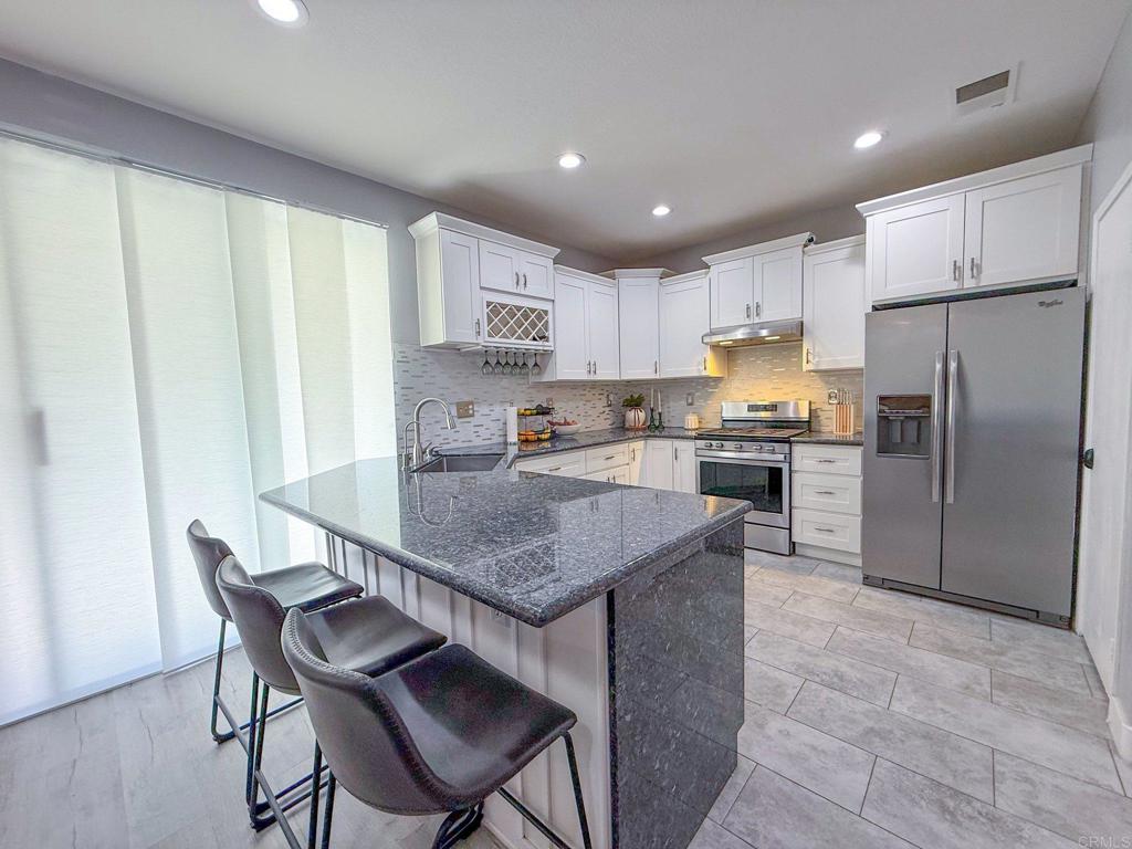 3237 Warley Road Hemet, CA 92545 - Photo 16 of 43 a kitchen with kitchen island a refrigerator a stove a sink and white cabinets with wooden floor