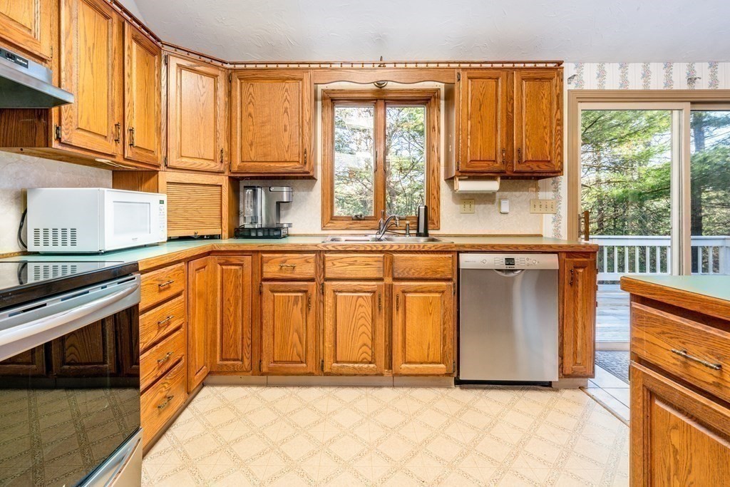 a view of a kitchen with stainless steel appliances granite countertop a stove and a window