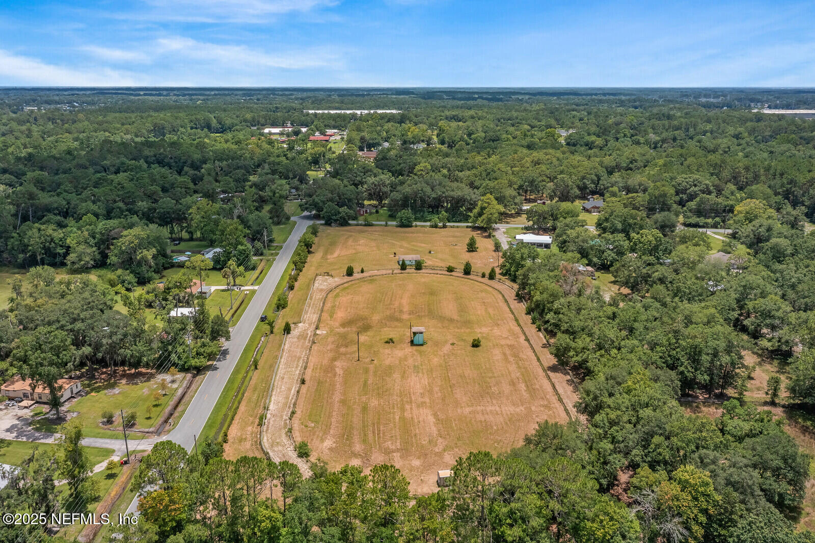an aerial view of residential houses with outdoor space and trees