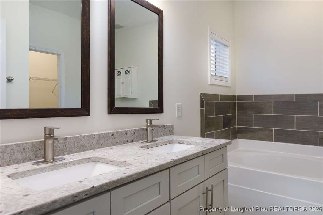 600 Burning Tree Road Pinehurst, NC 28374 - Photo 18 of 31 a bathroom with a granite countertop bathtub sink vanity and mirror
