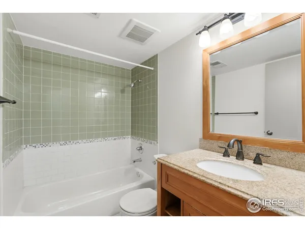 a bathroom with a granite countertop sink a mirror a bathtub and shower