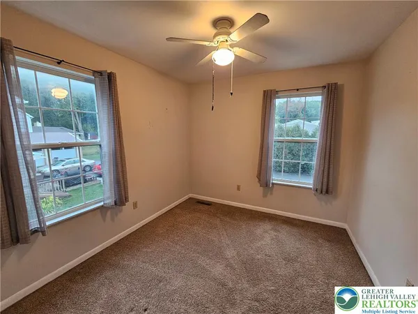 an empty room with windows and fan