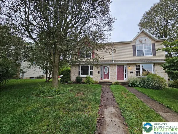 a front view of a house with a garden and trees