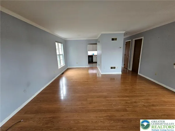a view of empty room with wooden floor and window