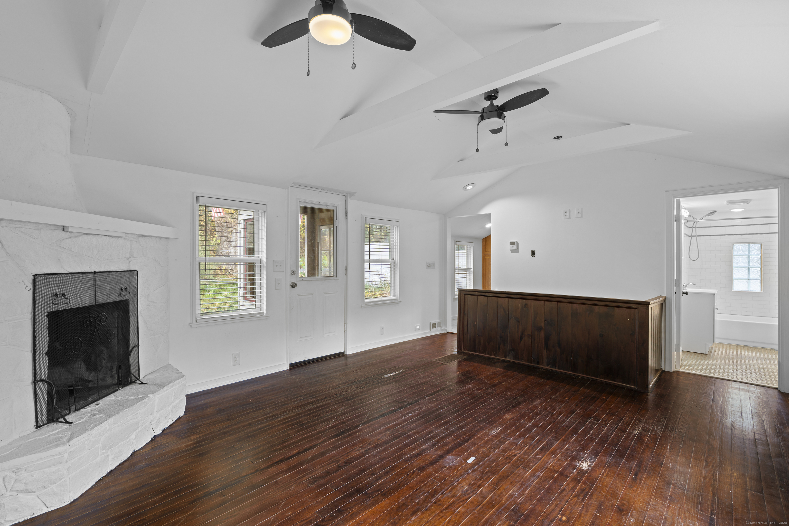 612 Kent Road New Milford, CT 06755 - Photo 9 of 35 an empty room with wooden floor a ceiling fan a fireplace and windows