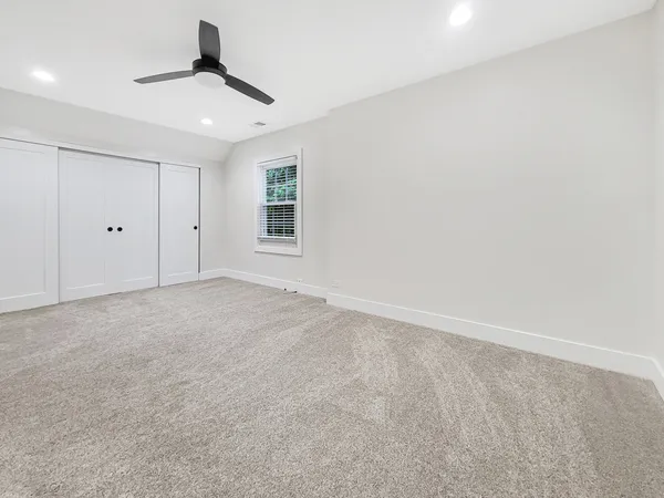an empty room with windows and ceiling fan