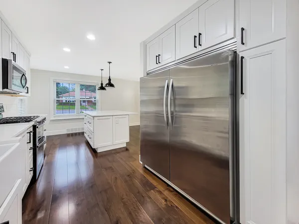 a kitchen with kitchen island wooden floor and stainless steel appliances