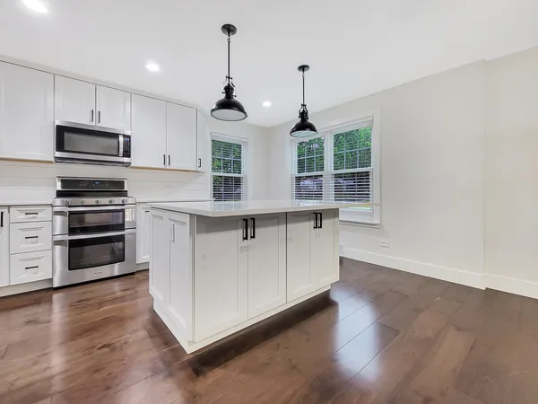 a kitchen with stainless steel appliances granite countertop a stove a sink and a wooden floor