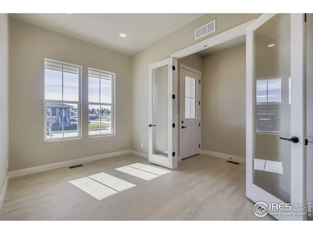 a open kitchen with stainless steel appliances kitchen island granite countertop a refrigerator a sink a stove and white cabinets with wooden floor