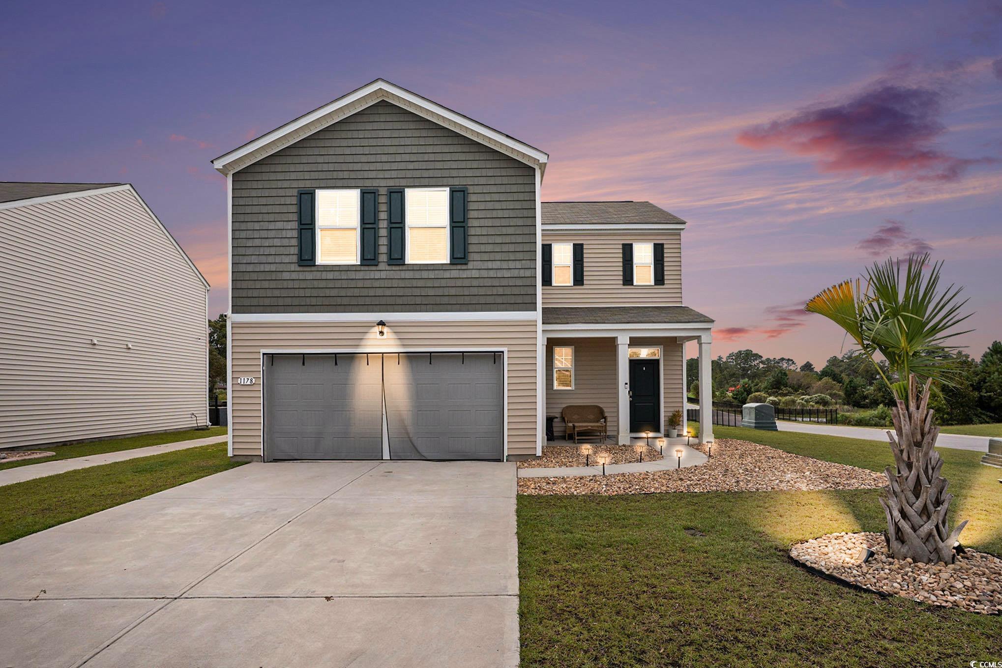 View of front of property with driveway, a front yard, a porch, a garage, and a shingled roof