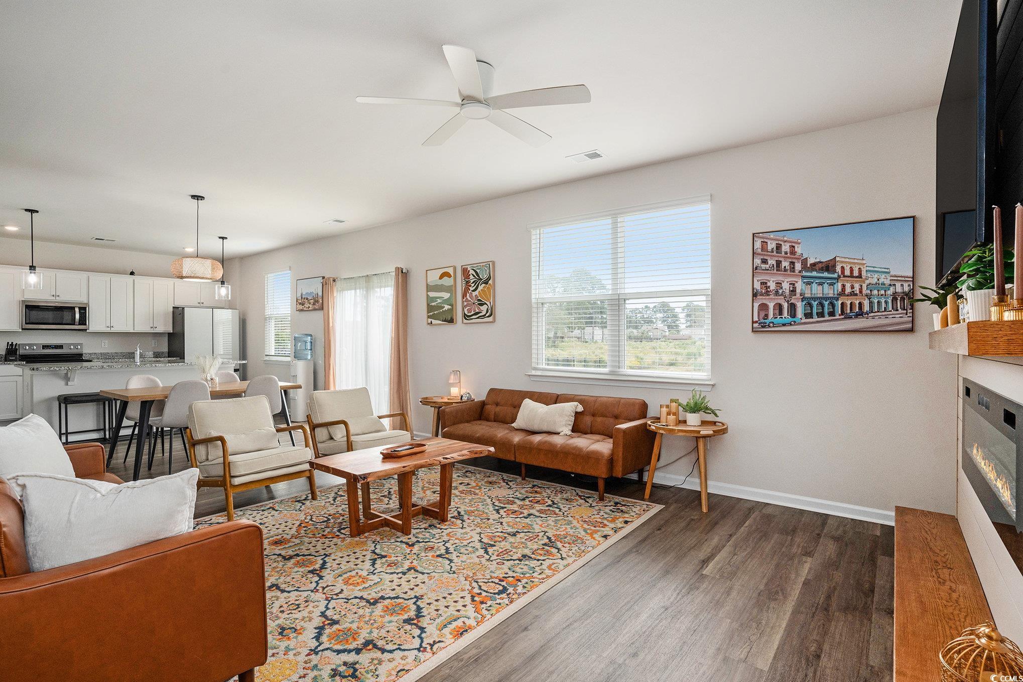 1178 Sennema Circle Myrtle Beach, SC 29588 - Photo 6 of 31 Living area featuring plenty of natural light, dark wood-type flooring, a glass covered fireplace, and a ceiling fan