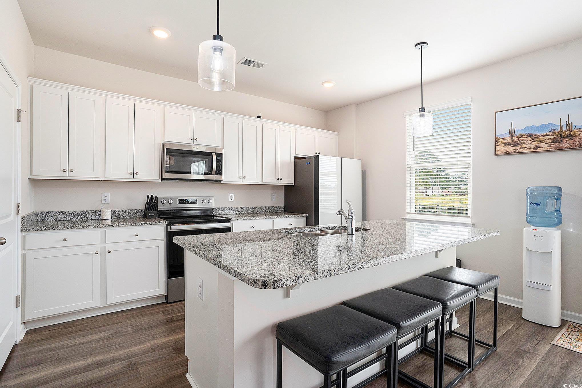 1178 Sennema Circle Myrtle Beach, SC 29588 - Photo 10 of 31 Kitchen featuring stainless steel appliances, a breakfast bar, white cabinets, light stone countertops, and recessed lighting