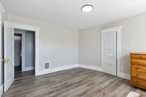 a view of an empty room with wooden floor and closet